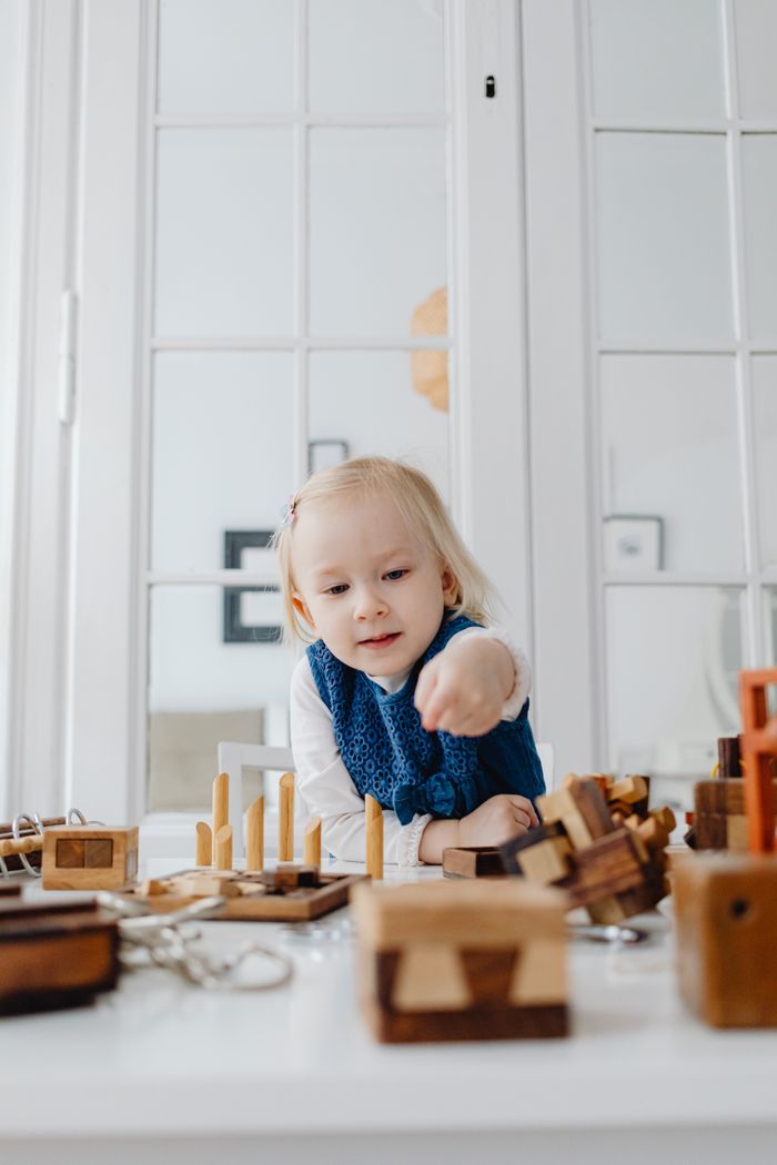 A child playing with wooden educational toys indoors, fostering creativity and learning.