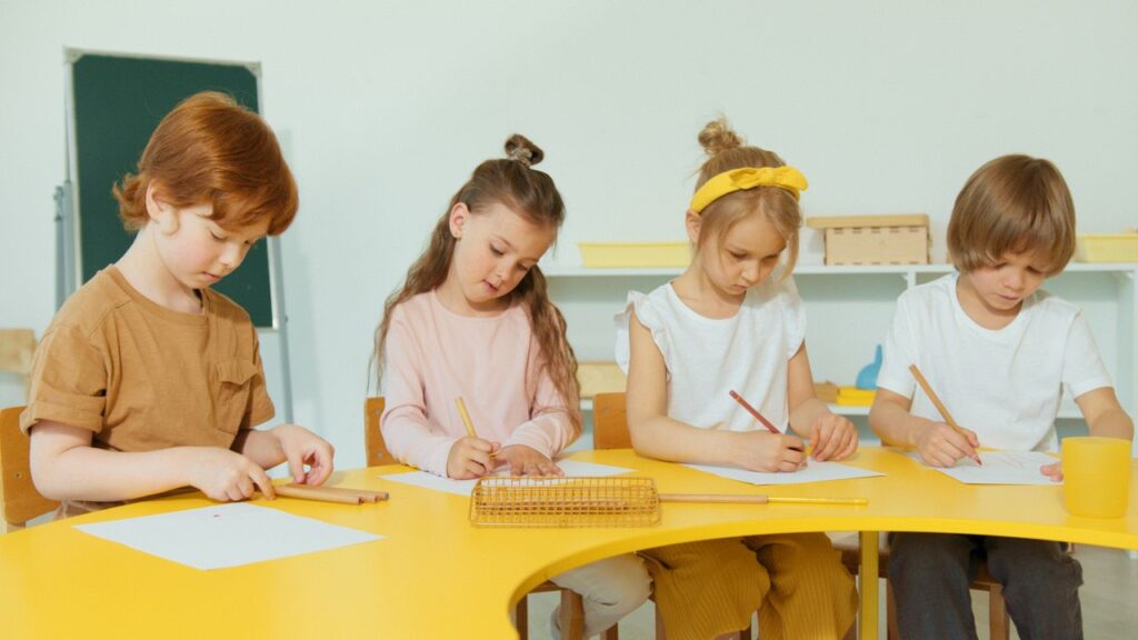 Group of children attentively writing and drawing during classroom learning activities.